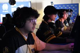 Five professional esports athletes sitting in a row at a gaming tournament, communicating through headsets with focused expressions